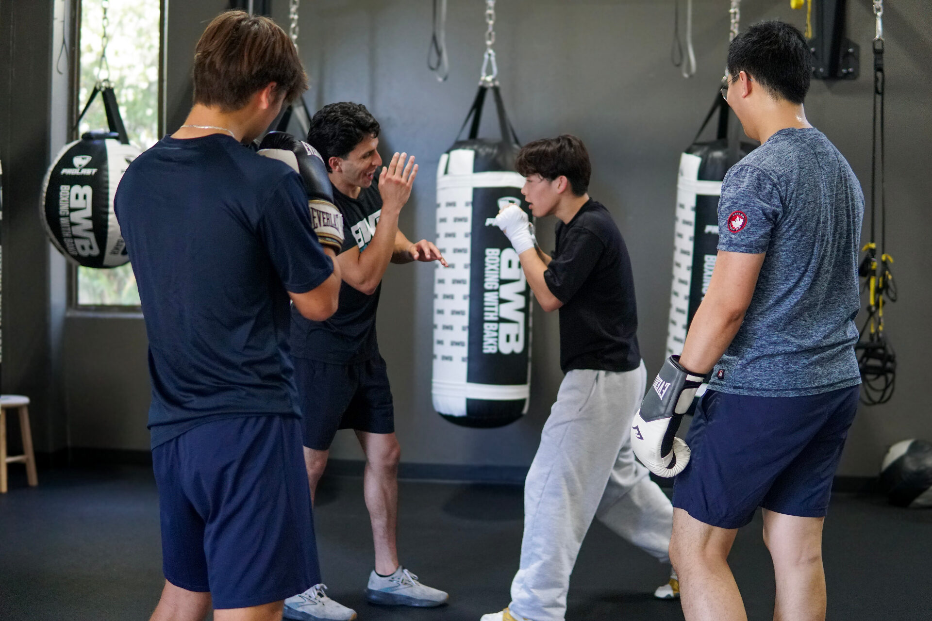 A small-group class circled around a heavy bag at Boxing With Bakr in Palo Alto